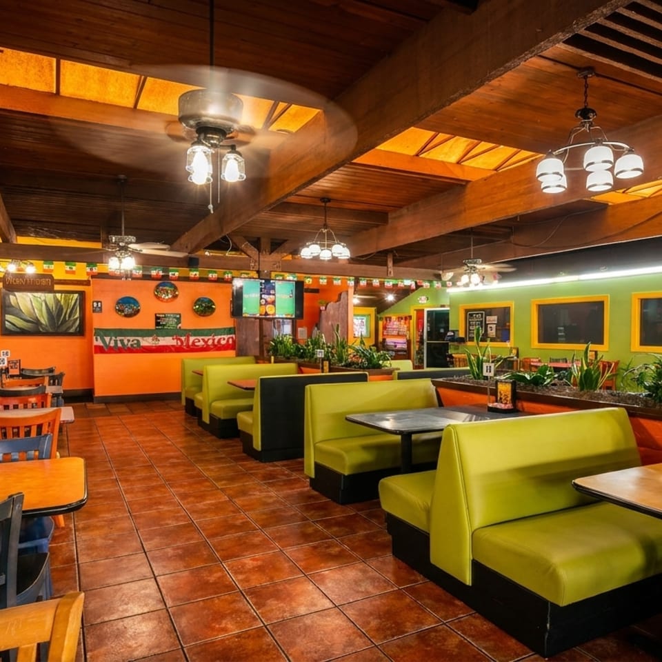 Vibrant Mexican restaurant interior with orange and green walls, wooden beams, and lime green booths.